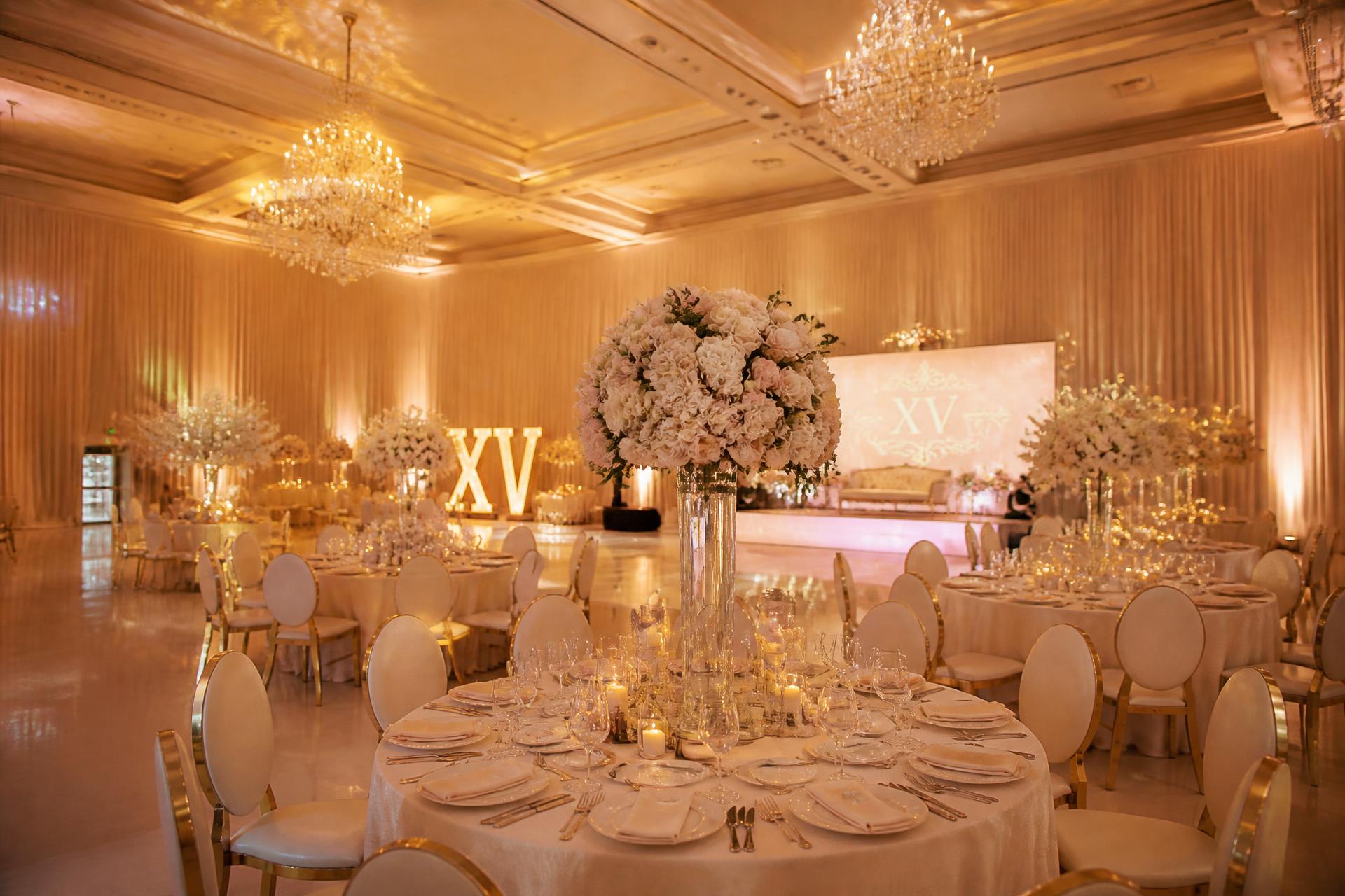 The Zion Venue event hall in Oakland set with ivory tables and warm golden lighting for a quinceañera